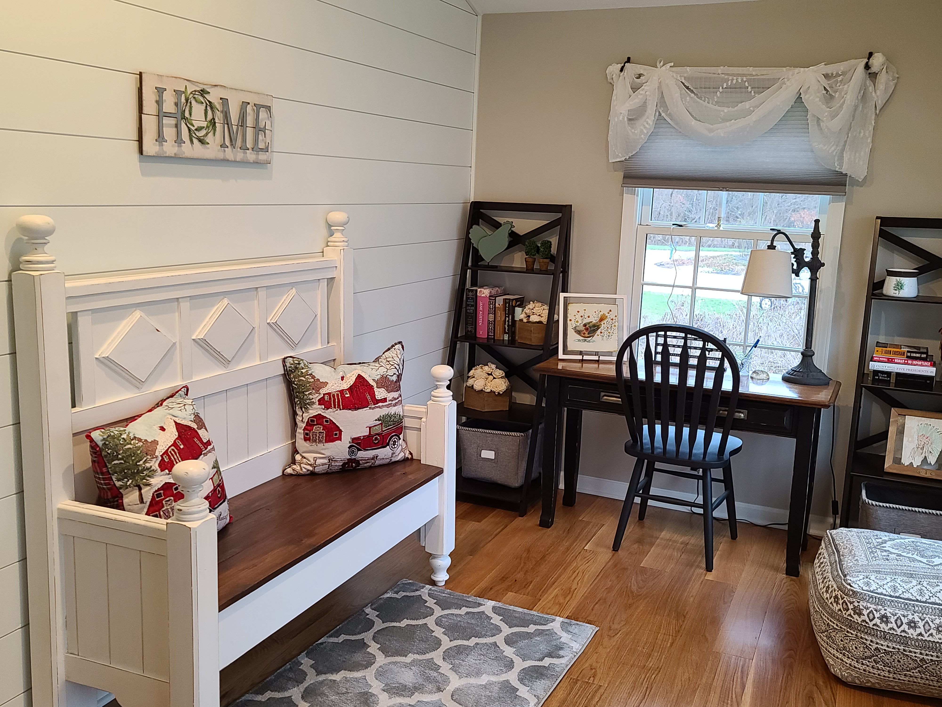 Farmhouse kitchen and dining area featuring a brick accent wall, white cabinetry with black appliances, a custom wooden range hood, and a dining table adorned with festive winter decor.
