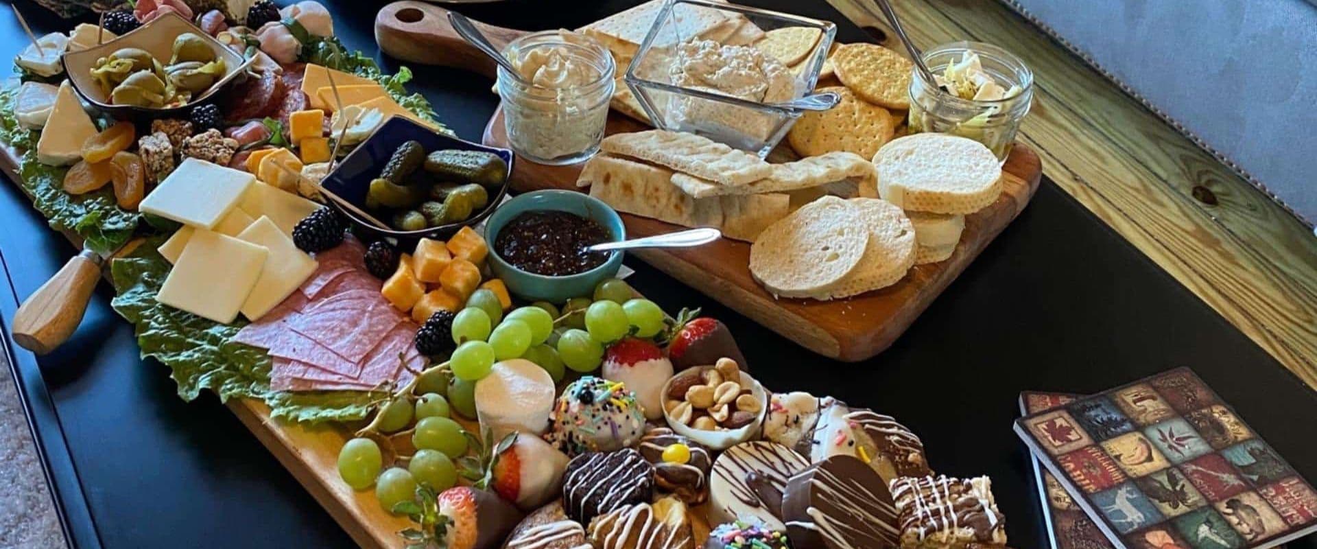 A colorful assortment of cheeses, meats, fruits, and sweet treats arranged on a wooden platter.