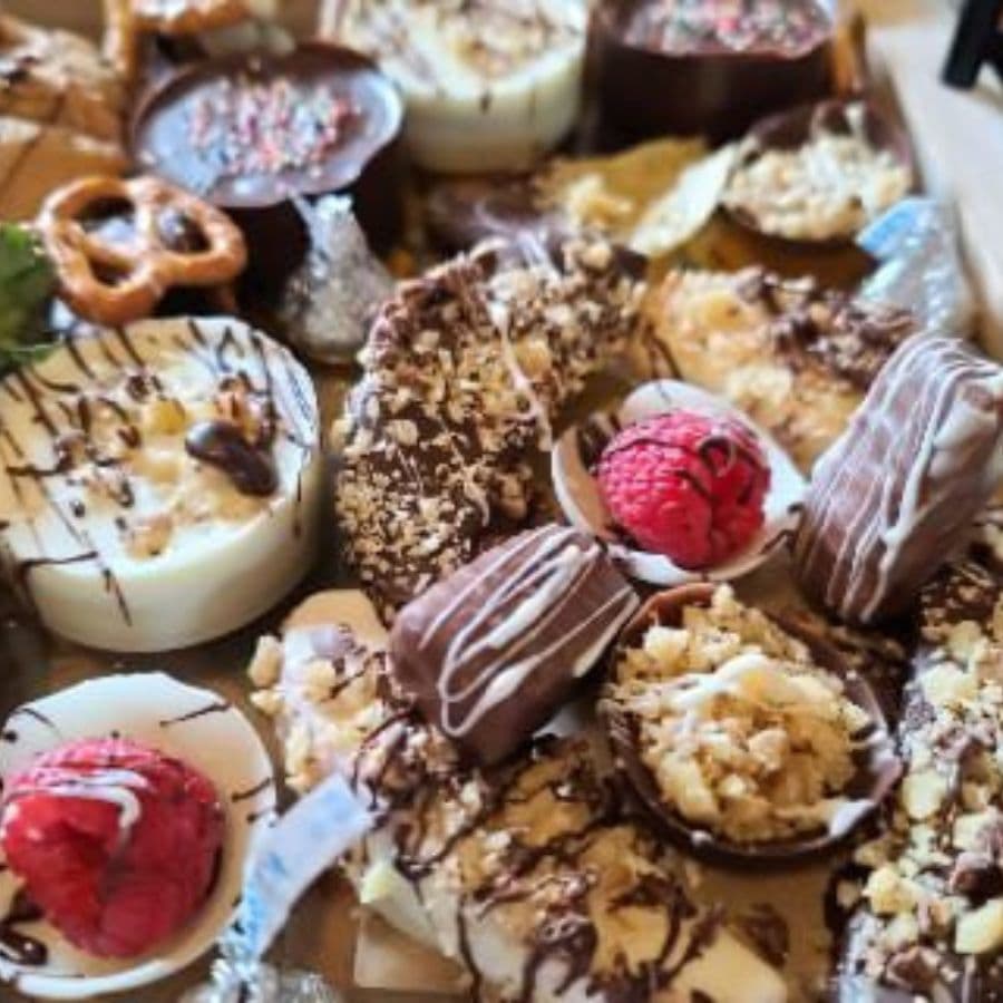 An assortment of decadent chocolates, desserts, and raspberries arranged on a platter.