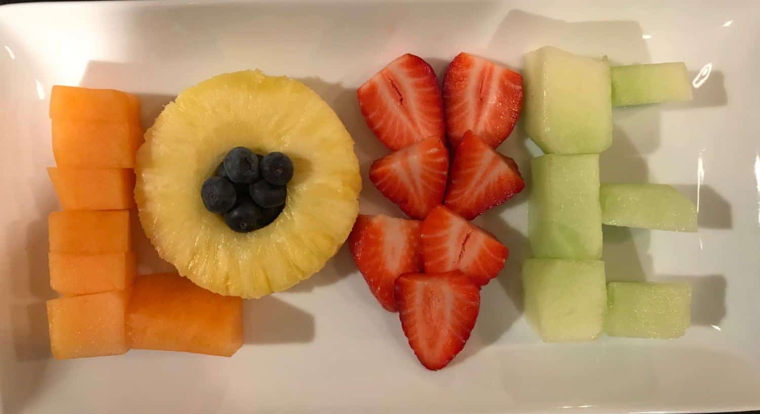 Cut up pieces of cantaloupe, pineapple, strawberries and honeydew arranged to spell the word LOVE