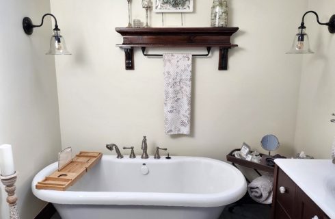 Bathroom with white walls, tile flooring, white claw foot tub, dark wooden vanity and white sink