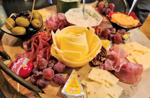 Charcuterie board filled with cheese, meat, pickles, crackers, and fruit