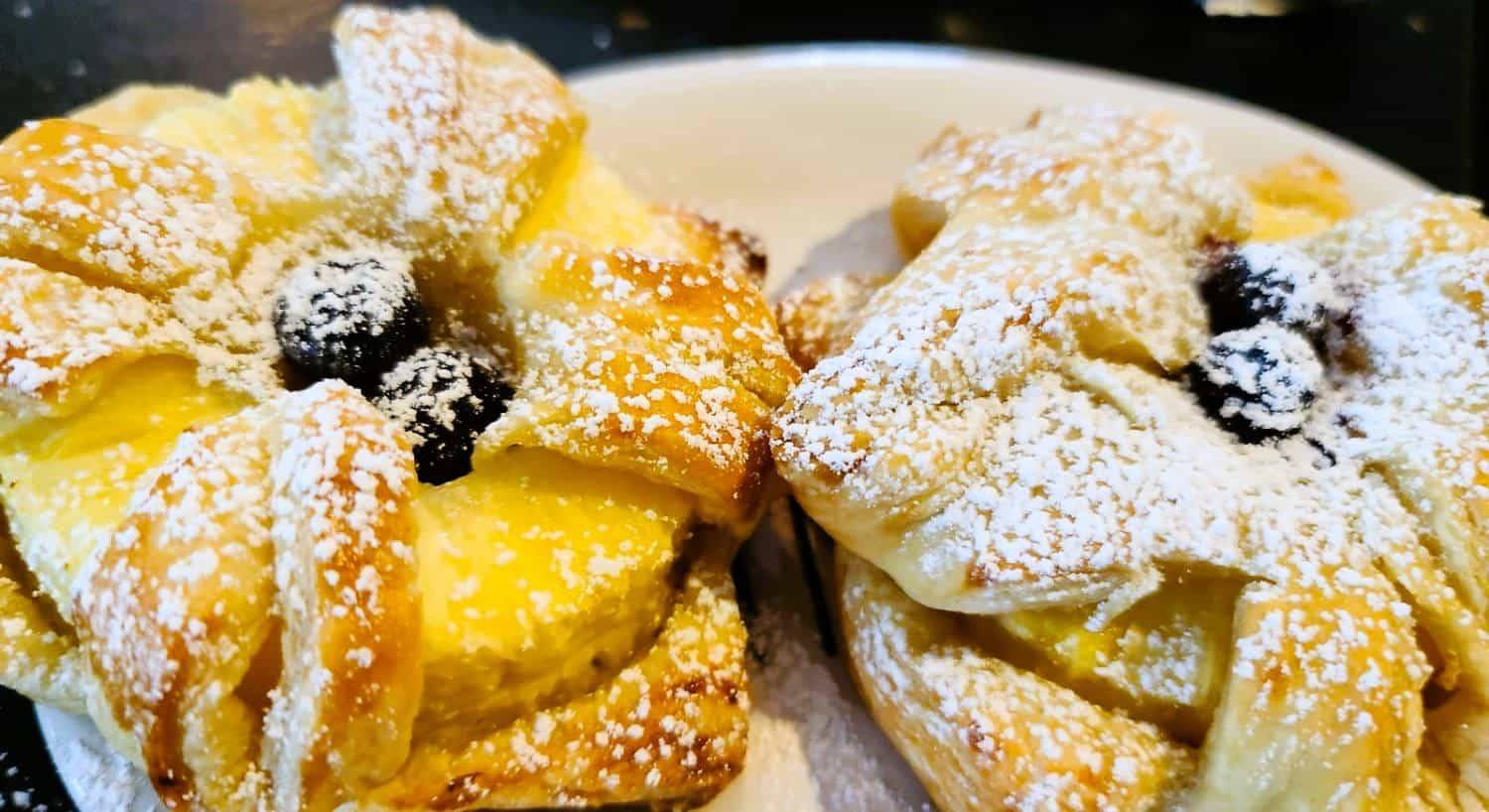 Close up view of pineapple pastries dusted with powdered sugar on a white plate
